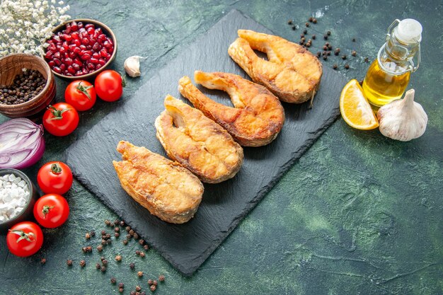 Vorderansicht leckeren gebratenen Fisch mit Tomaten auf dunkelblauer Oberfläche Kochgericht Essenssalat Braten Mahlzeit Meeresfrüchte Pfeffer Meeresfleisch