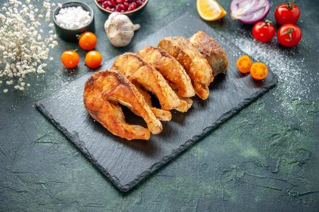 Vorderansicht leckeren gebratenen Fisch mit Tomaten auf dunkelblauer Oberfläche Mahlzeit Pfeffergericht braten Meeresfrüchte Meeresfleisch Lebensmittel Salat