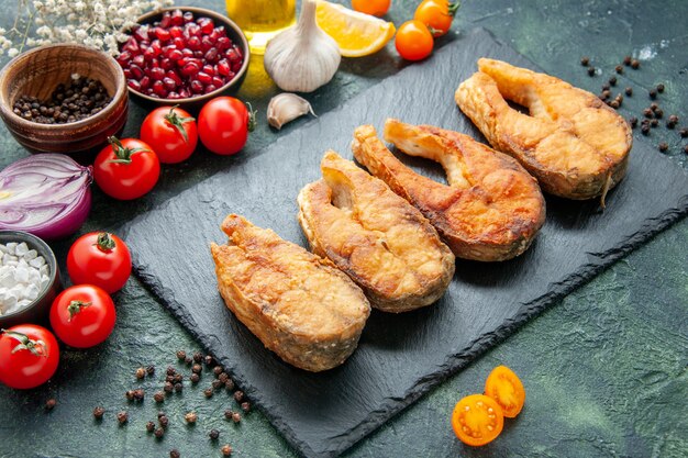 Vorderansicht leckeren gebratenen Fisch mit Tomaten auf dunkler Oberfläche Kochgericht Salat Braten Mahlzeit Meeresfrüchte Pfeffer Meeresfleisch Essen