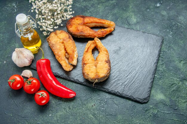 Vorderansicht leckeren gebratenen Fisch mit Tomaten und rotem Pfeffer auf dunklem Hintergrund Kochsalat Mahlzeit Essen Meeresfrüchte Fleisch Meeresfrüchte braten