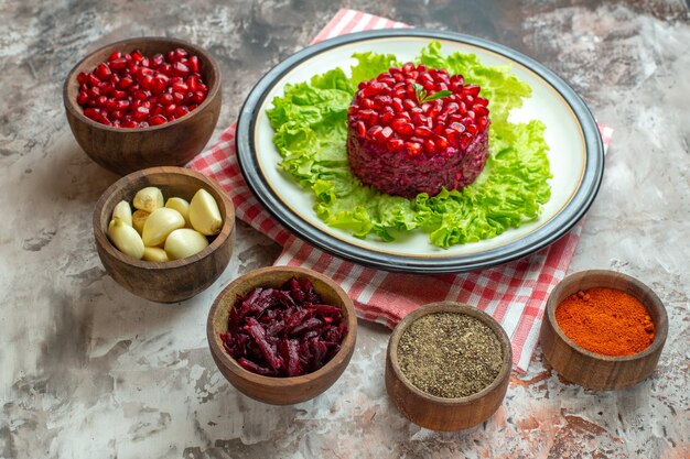 Vorderansicht leckerer Granatapfelsalat auf grünem Salat mit Gewürzen auf hellem Fotoessen Mahlzeit Farbe gesunde Ernährung lecker