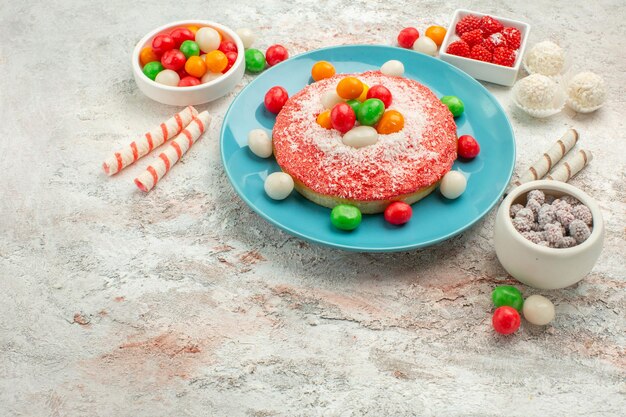 Vorderansicht leckerer rosa Kuchen mit bunten Bonbons auf weißem Hintergrund Süßigkeiten Dessert Farbe Regenbogen Goodie Cake