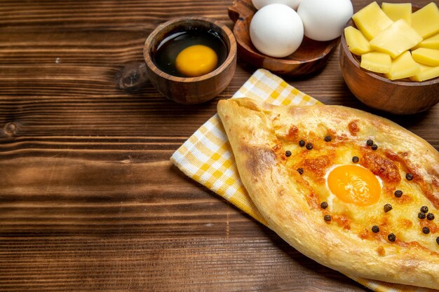 Vorderansicht leckeres Eierbrot frisch aus dem Ofen mit Käse auf braunem Schreibtisch Teig backen Brötchen