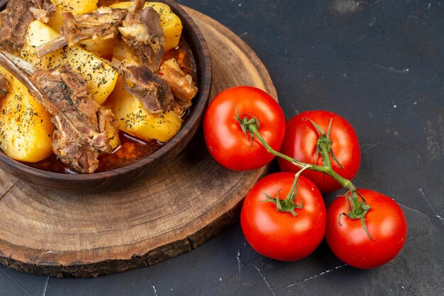 Vorderansicht leckeres gekochtes fleisch mit gekochten kartoffeln und tomaten auf dunklem hintergrund gerichtssoße kochen küche heiße fleischküche
