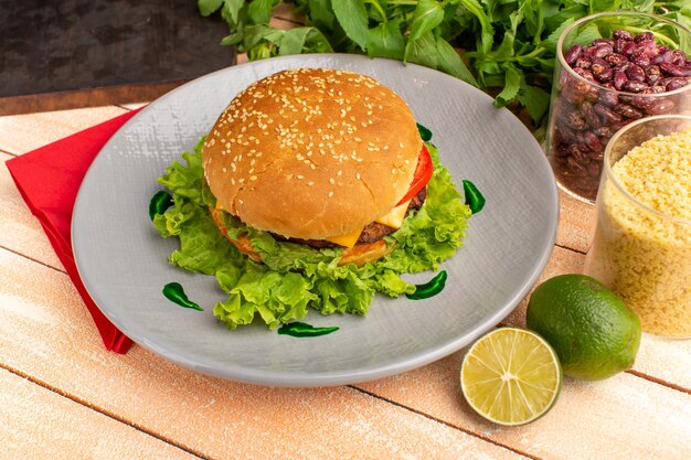 Vorderansicht leckeres Hühnchensandwich mit grünem Salat und Gemüse innerhalb Platte auf dem hölzernen Sahne-Schreibtisch.