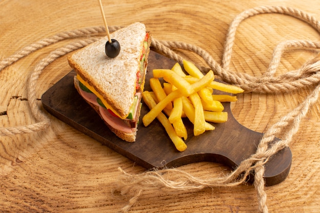 Kostenloses Foto vorderansicht leckeres sandwich mit olivenschinken tomaten gemüse zusammen mit pommes frites seilen auf holz