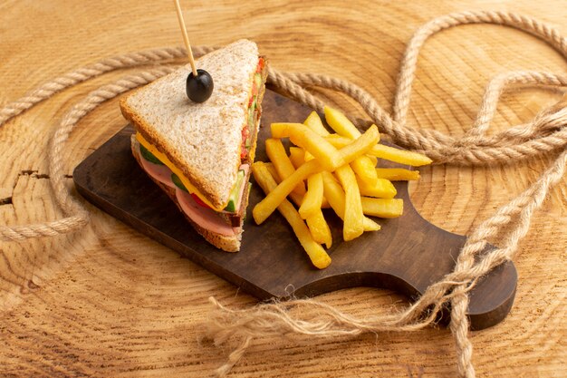 Vorderansicht leckeres Sandwich mit Olivenschinken Tomaten Gemüse zusammen mit Pommes Frites Seilen auf Holz