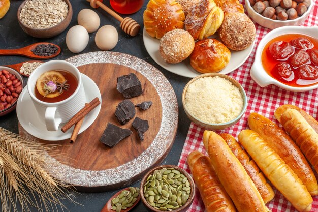 Vorderansicht leckeres süßes Gebäck mit Gelee-Tee und Brötchen auf dunkler Wand