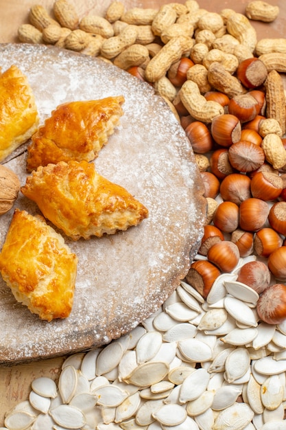 Vorderansicht leckeres Walnussgebäck mit Nüssen auf leichtem Tischkuchenkuchen süßes Gebäck