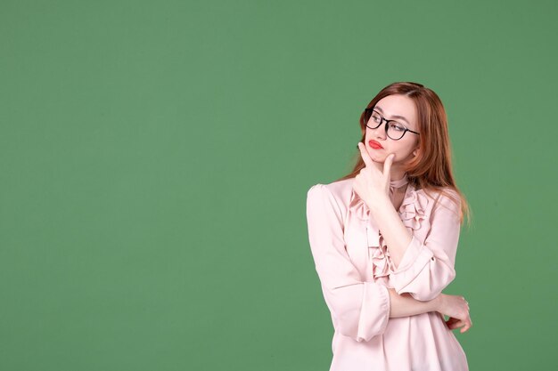 Vorderansicht Lehrerin in rosa Bluse auf grünem Hintergrund Schule Farbbibliothek College Job junges Buch Lektion Arbeit Frau