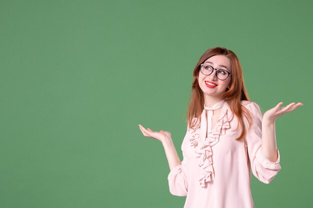 Vorderansicht Lehrerin in rosa Bluse mit Blick auf etwas auf grünem Hintergrund Job Bibliothek Schule Frau junge Arbeitsfarbe Schüler Lektion Buch College