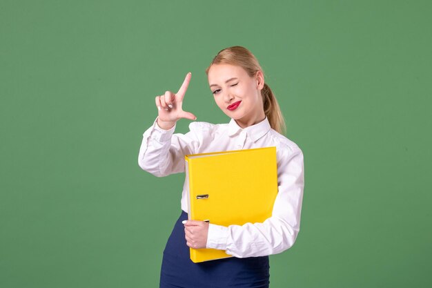 Vorderansicht Lehrerin in strenger Kleidung mit gelben Dateien auf Grün