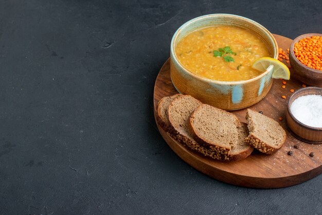 Vorderansicht Linsensuppe mit Salz rohen Linsen und dunklen Brotlaib auf dunkler Oberfläche