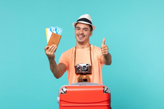 Vorderansicht männlich im Urlaub, der seine Tickets auf blauem Boden Reise Urlaubsreise Reise Wasserflugzeug hält