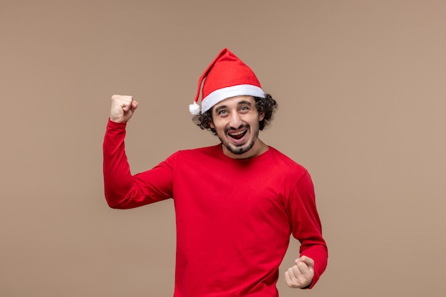 Vorderansicht männlich in der roten Freude auf braunem Hintergrundfeiertagsemotionsweihnachten