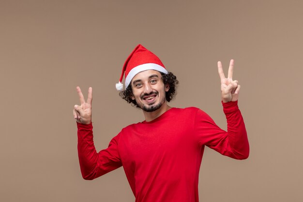 Vorderansicht männlich in rot mit lächelndem Gesicht auf braunem Hintergrundfeiertagsemotionsweihnachten