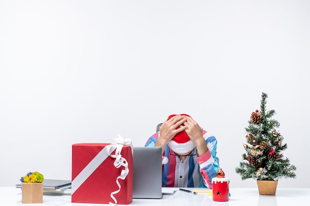 Vorderansicht männlicher arbeiter, der an seinem arbeitsplatz sitzt, betonte weihnachtsgeschäfts-jobgefühle