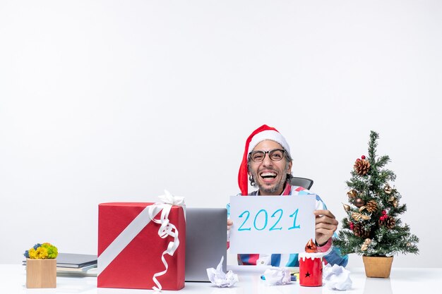 Vorderansicht männlicher Arbeiter, der an seinem Arbeitsplatz sitzt und Notiz mit dem Schreiben des neuen Jahresjobs Weihnachten Neujahr hält