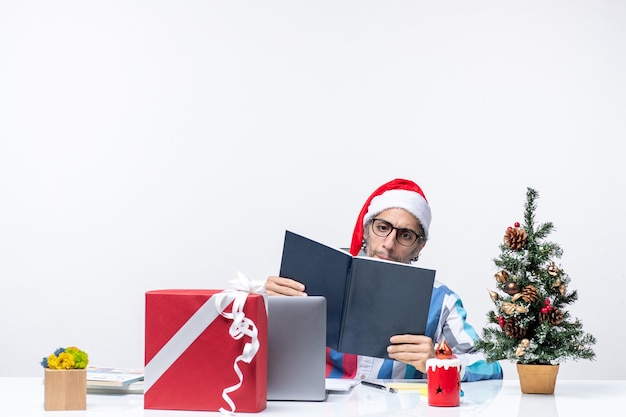 Vorderansicht männlicher Arbeiter, der an seinem Arbeitsplatz sitzt und Schreibheft-Geschäftsjob-Emotion-Weihnachtsbüro liest