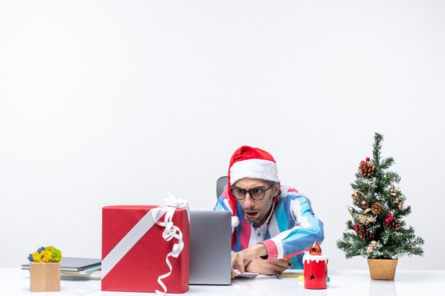 Vorderansicht männlicher Arbeiter, der an seinem Platz sitzt, Notizen schreibt und Laptop-Emotion-Büro-Weihnachtsjob verwendet