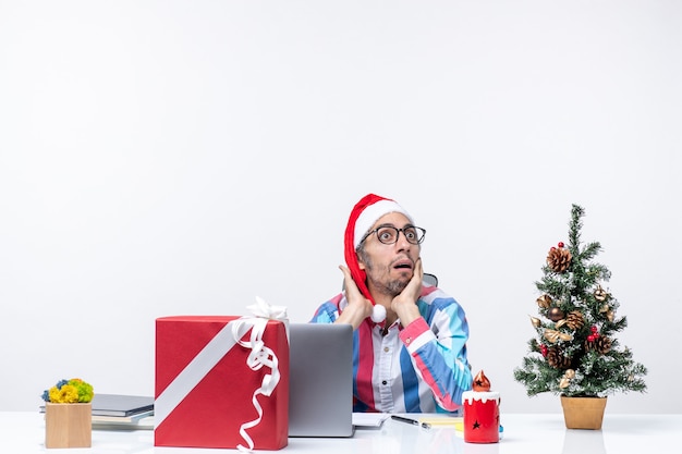 Vorderansicht männlicher Arbeiter sitzt an seinem Arbeitsplatz Bürojob Weihnachtsgeschäft Emotion