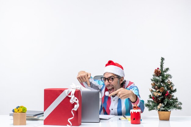 Vorderansicht männlicher Arbeiter sitzt an seinem Platz mit Laptop-Emotionen-Büro-Weihnachtsjob