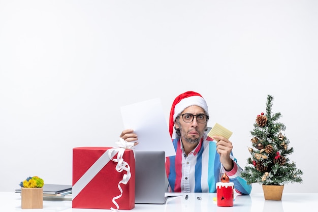 Vorderansicht männlicher Arbeiter sitzt an seinem Platz mit Laptop hält Dokumente Emotion Bürojob Weihnachten