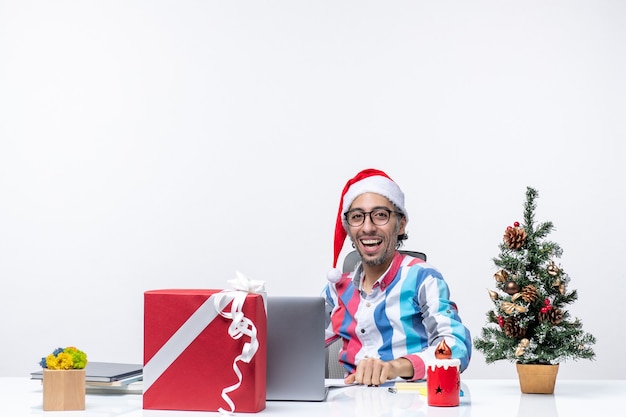 Vorderansicht männlicher arbeiter sitzt an seinem platz mit laptop hält dokumente job emotionen büro weihnachten