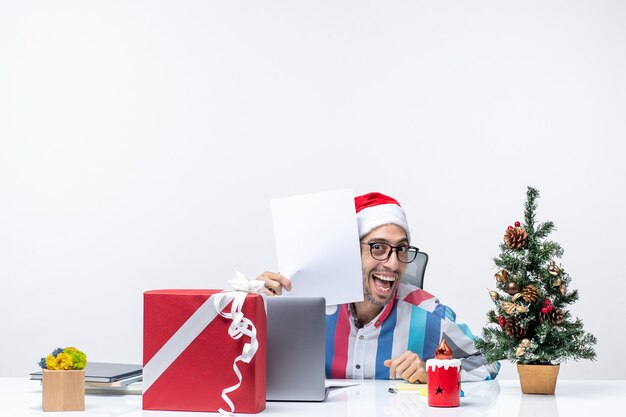 Kostenloses Foto vorderansicht männlicher arbeiter sitzt an seinem platz mit laptop hält dokumente