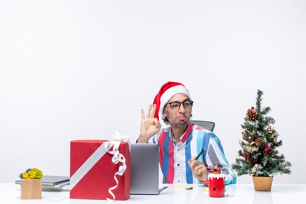 Vorderansicht männlicher Arbeiter sitzt an seinem Platz mit Laptop und Akten posiert