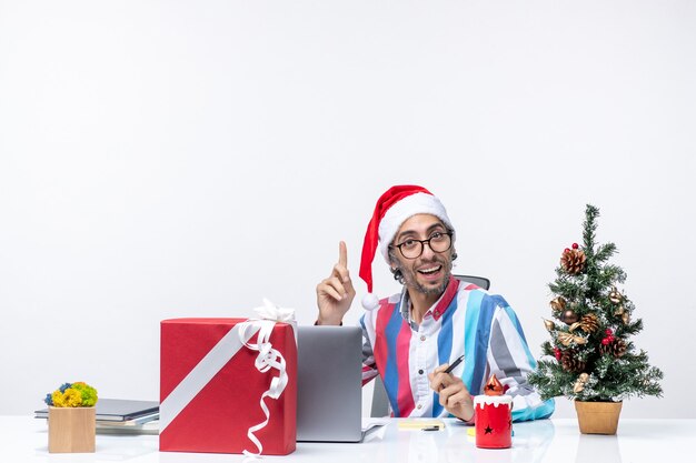Vorderansicht männlicher Arbeiter sitzt an seinem Platz mit Laptop und Dateien, die Büroferienjob Weihnachten arbeiten