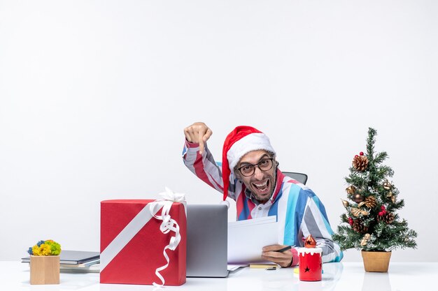 Vorderansicht männlicher Arbeiter sitzt an seinem Platz mit Laptop und Dateien mit Dokumenten Weihnachten Neujahr Job Büro Emotionen