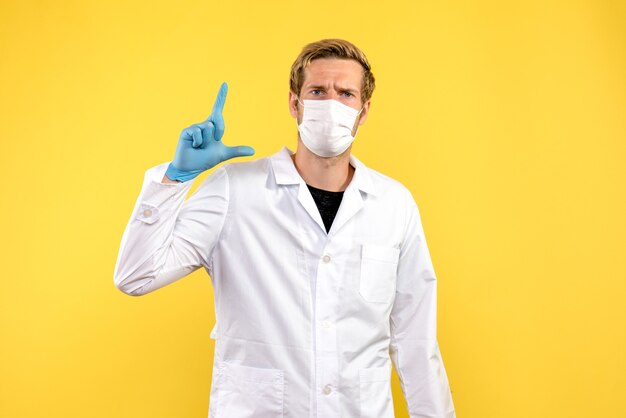 Vorderansicht männlicher Arzt auf gelbem Hintergrund Gesundheitsmediziner Pandemie covid