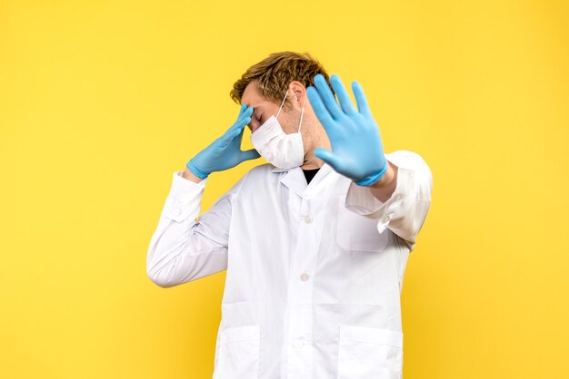 Vorderansicht männlicher Arzt auf gelbem Hintergrund Gesundheitspandemie Covid Medic