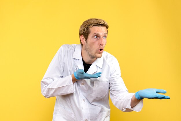 Vorderansicht männlicher Arzt auf gelbem Hintergrund menschlicher covid Krankenhausmediziner