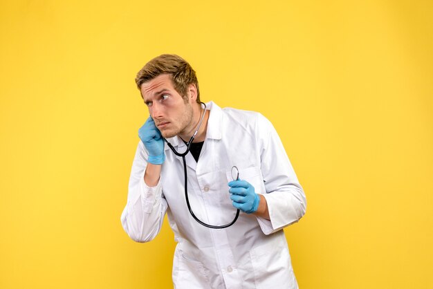 Vorderansicht männlicher Arzt auf gelbem Hintergrund Virus Gesundheit Emotion Sanitäter