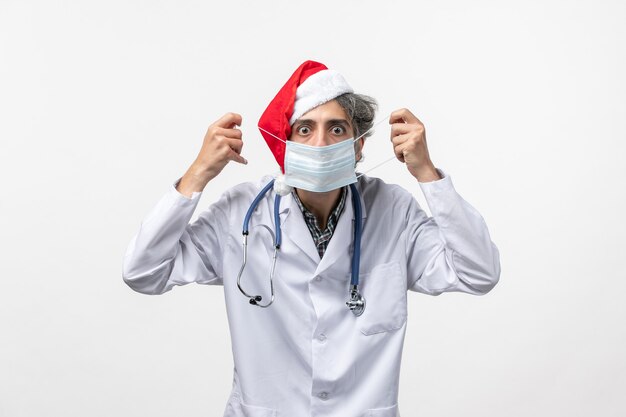 Vorderansicht männlicher Arzt, der Maske auf weißer Wand Neujahrsfeiertagsvirus covid trägt