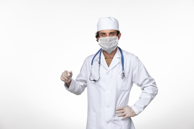 Vorderansicht männlicher Arzt im medizinischen Anzug mit Maske als Schutz vor Covid-on-White-Wall-Virus-Krankheit Covid-Pandemie