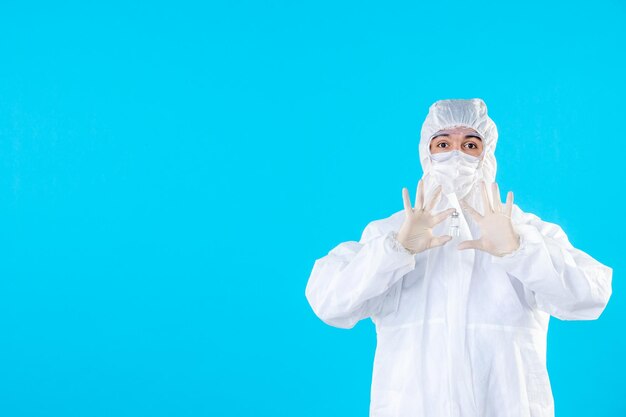 Vorderansicht männlicher Arzt in Schutzanzug und Maske auf dem Blau