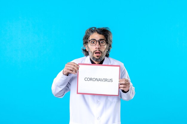 Vorderansicht männlicher Arzt mit Coronavirus-Schriftzug auf Blau