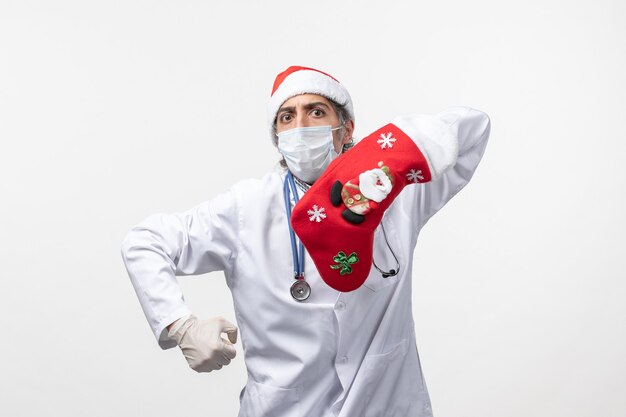Vorderansicht männlicher Arzt mit großer roter Socke auf weißem Bodenvirus covid-Weihnachtsfeiertag