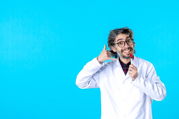 Vorderansicht männlicher Arzt mit Injektion lächelnd auf Blau