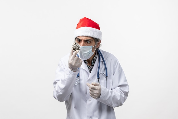 Vorderansicht männlicher Arzt mit Neujahrsbaumspielzeug auf weißem Bodenvirusgesundheits-Covid-
