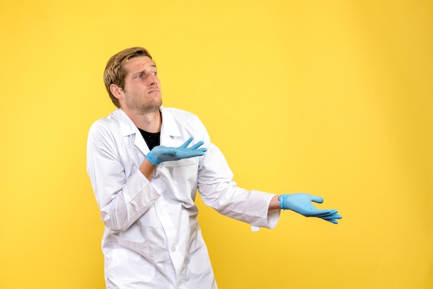 Vorderansicht männlicher Arzt verwirrt auf dem gelben Hintergrund Covid-Pandemie-Gesundheitsmediziner