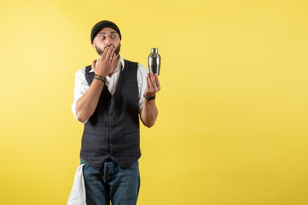 Vorderansicht männlicher Barkeeper, der kleinen silbernen Shaker auf gelber Wand hält Modell trinken Arbeit Job Club männliche Nacht