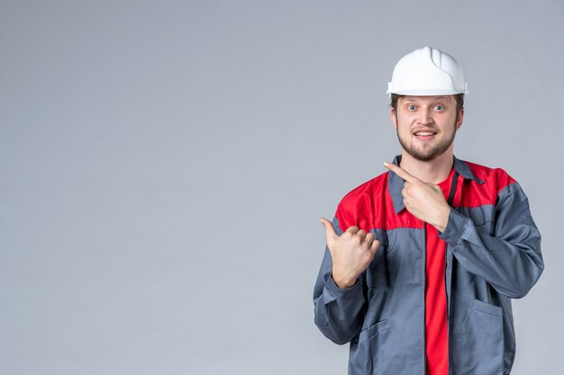 Vorderansicht männlicher Baumeister in Uniform und Helm auf grauem Hintergrund