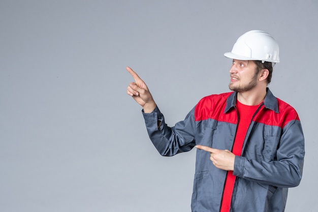 Vorderansicht männlicher Baumeister in Uniform und Helm auf grauem Hintergrund