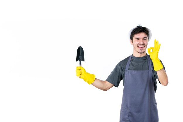 Vorderansicht männlicher Gärtner in gelben Handschuhen mit kleinem Spachtel auf weißem Hintergrund Baumfarbe Blumengarten Bodenarbeit Buschgras Job