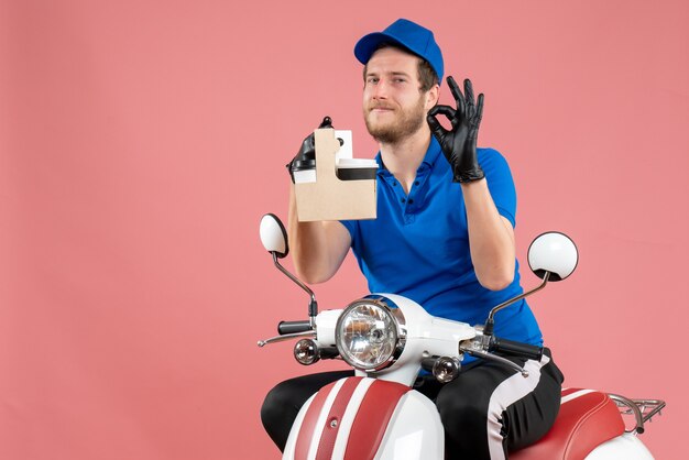 Vorderansicht männlicher Kurier in blauer Uniform, der Kaffee auf dem rosa Job hält, Fast-Food-Lieferservice für Fahrradservice-Arbeiter in Farbe