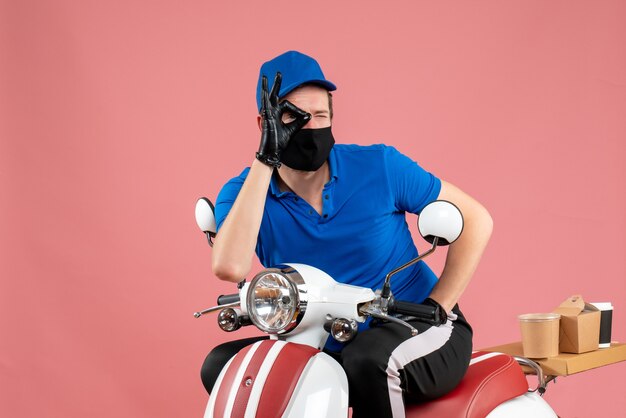 Vorderansicht männlicher Kurier in blauer Uniform und Maske auf rosa Job-Fast-Food-Service-Fahrradarbeit Covid-Food-Virus